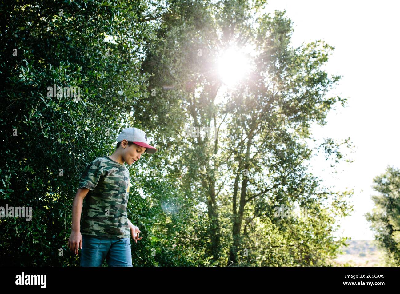 Profilo di un ragazzo che indossa una camicia camouflage mentre fuori in natura Foto Stock