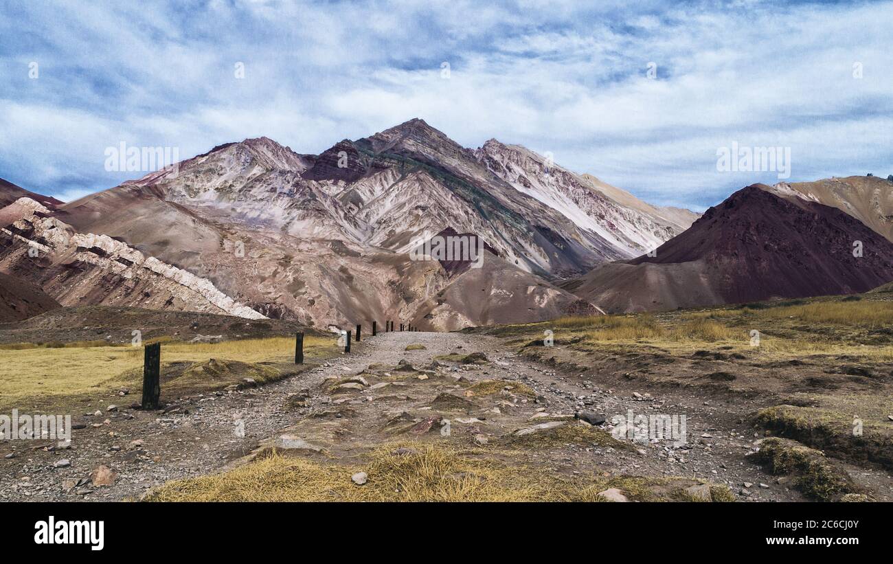 Vista delle colorate montagne sul sentiero in pietra del parco Aconcagua in autunno in una giornata nuvolosa Foto Stock