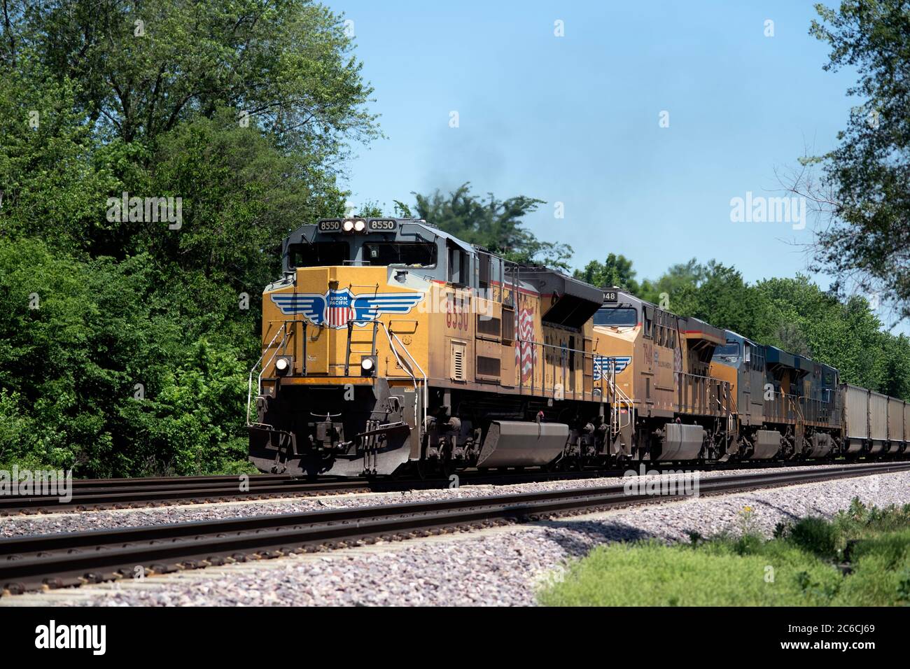 Lafox, Illinois, Stati Uniti. Quattro locomotive, tra cui due unità CSX fuoristrada, guidano un treno merci Union Pacific di auto a carbone vuoto attraverso Lafox, Illinois Foto Stock