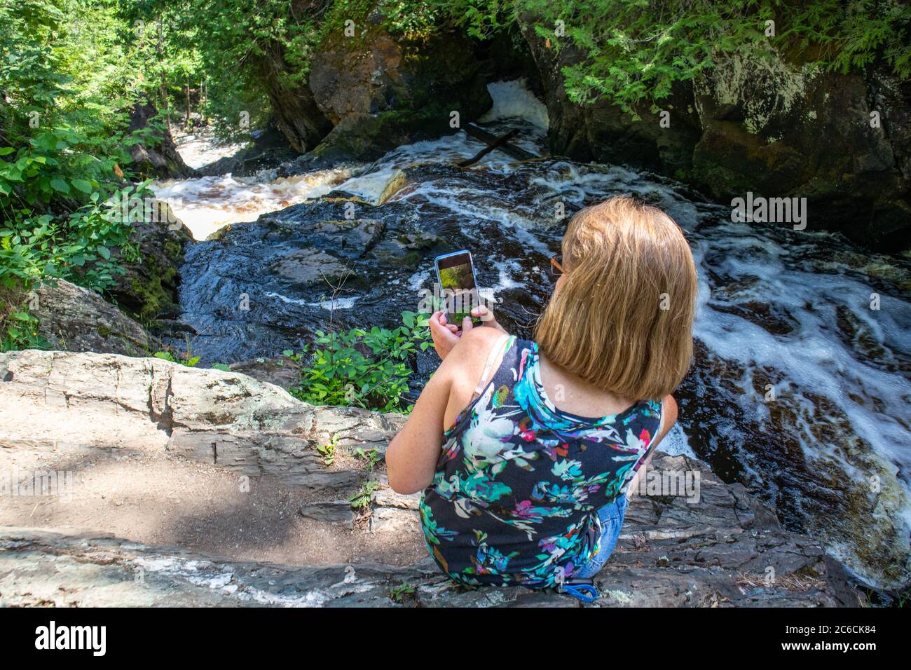 Lady scattando una foto di un fiume Wisconsin con il suo smartphone, orizzontale Foto Stock