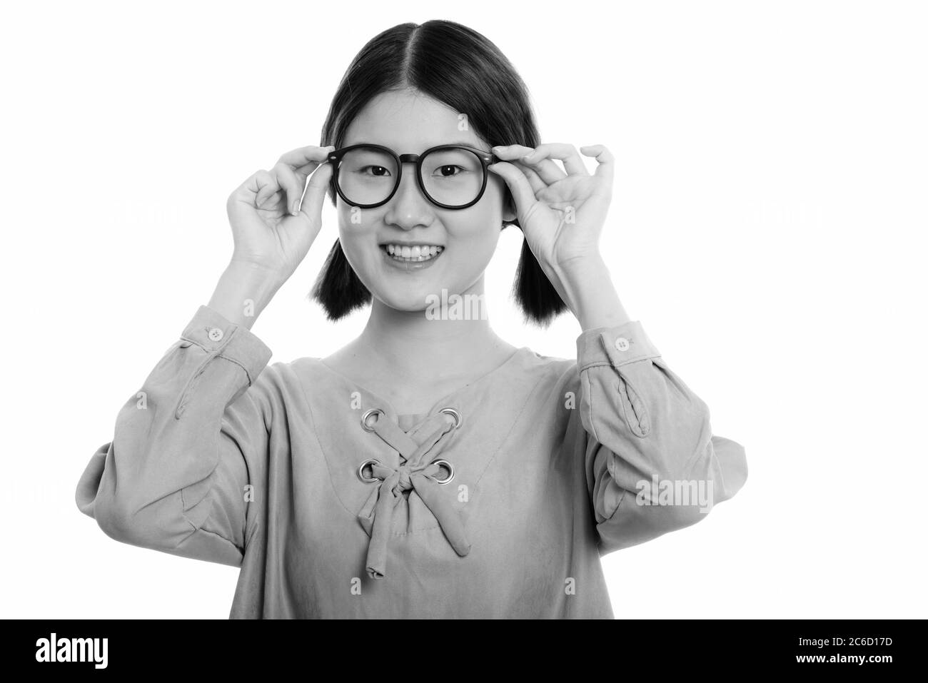 Studio di giovane donna asiatica felice sorridente mentre tiene gli occhiali con entrambe le mani Foto Stock