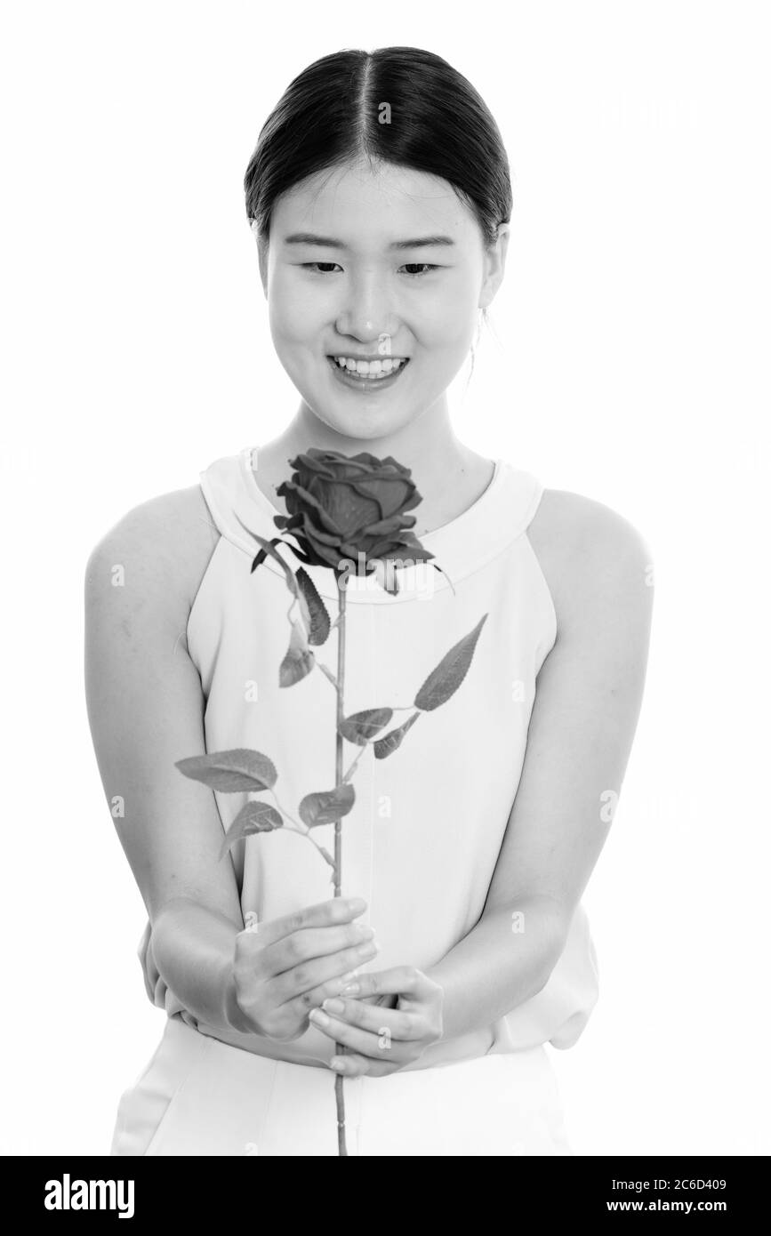 Studio di una giovane donna asiatica felice sorridente e con rosa rossa Foto Stock