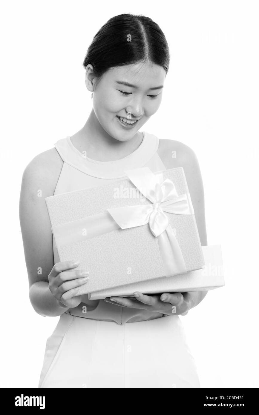Studio scatto di giovane felice donna asiatica sorridente mentre apre scatola regalo Foto Stock