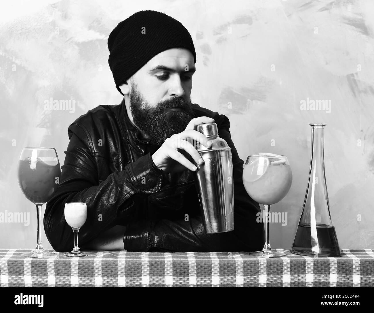 Uomo Barbuto, barba lunga. Brutale caucasian hipster con baffi in rock nero stile azienda shaker e bicchieri di cocktail alcolico con tiro sul blu scozzese a scacchi sulla texture di sfondo per studio Foto Stock