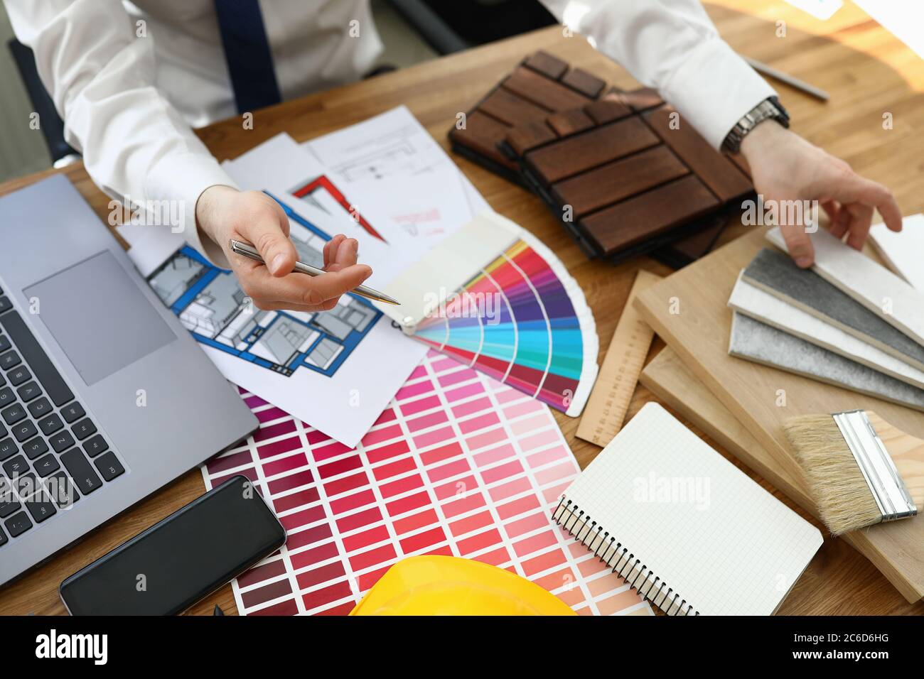 L'uomo in ufficio si siede al tavolo con una tavolozza di colori per gli interni Foto Stock