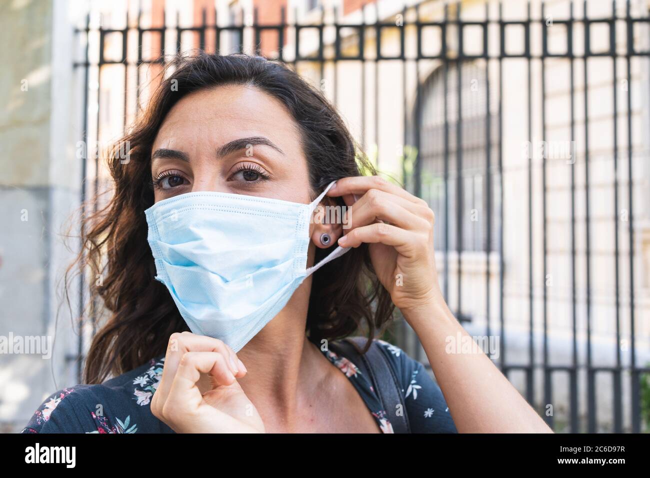 Giovane donna che si è indossata una maschera chirurgica per la strada per proteggersi e adottare misure igieniche di sicurezza. Concetto di protezione e sicurezza Foto Stock