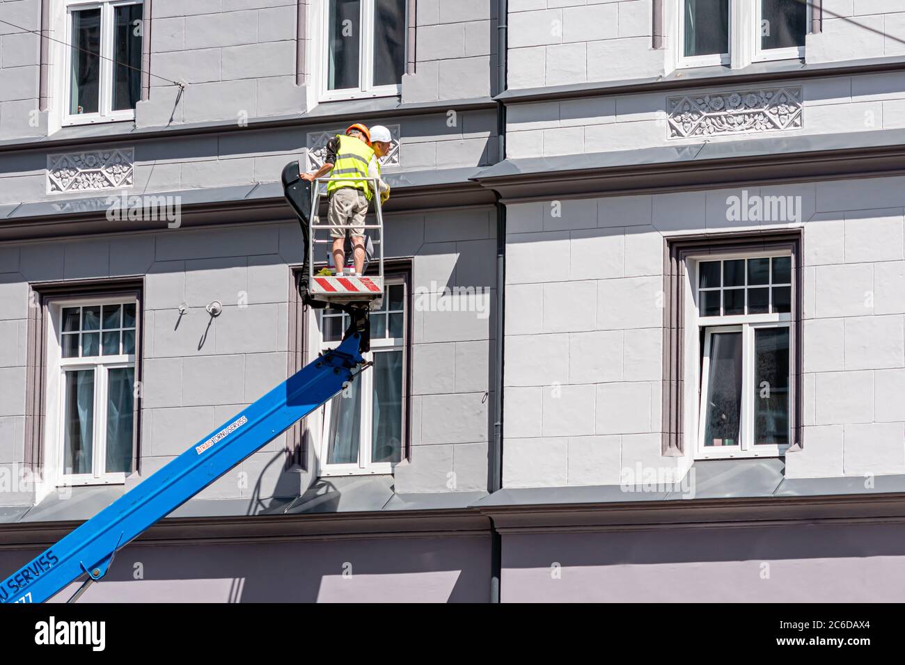 Riga, Lettonia - 3 luglio 2020: Il lavoratore di costruzione su una piattaforma di sollevamento idraulico ispeziona le condizioni dei tubi di scarico Foto Stock