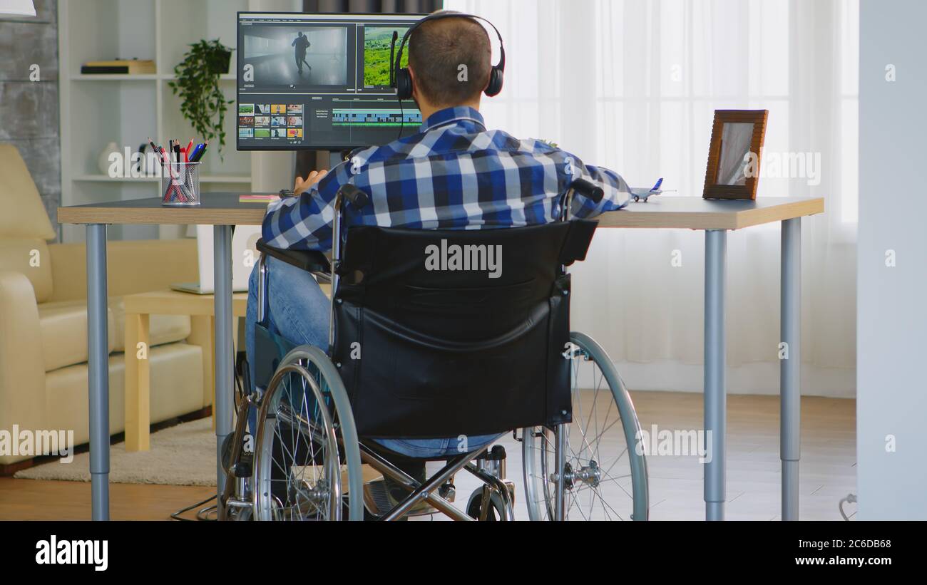 Video editor disabilitato seduto su sedia a rotelle che fa post produzione  su film Foto stock - Alamy