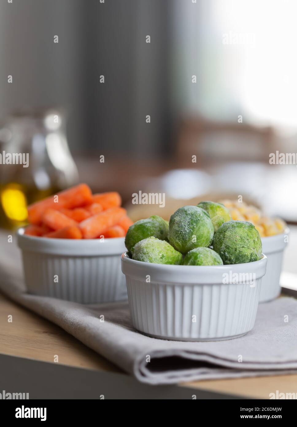 Verdure surgelate come carote per bambini e germogli di Bruxelles nelle ciotole sul tavolo da cucina. Il congelamento è un metodo sicuro per aumentare la durata di conservazione di Foto Stock