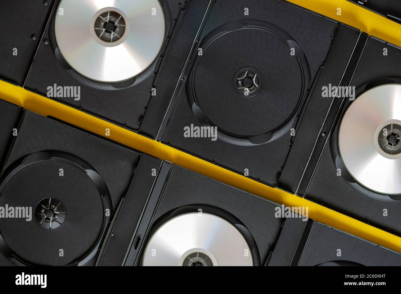 Sfondo creativo con DVD e dischi blu-ray su giallo. Aprire le scatole nere con i cd. Vista dall'alto. Foto Stock