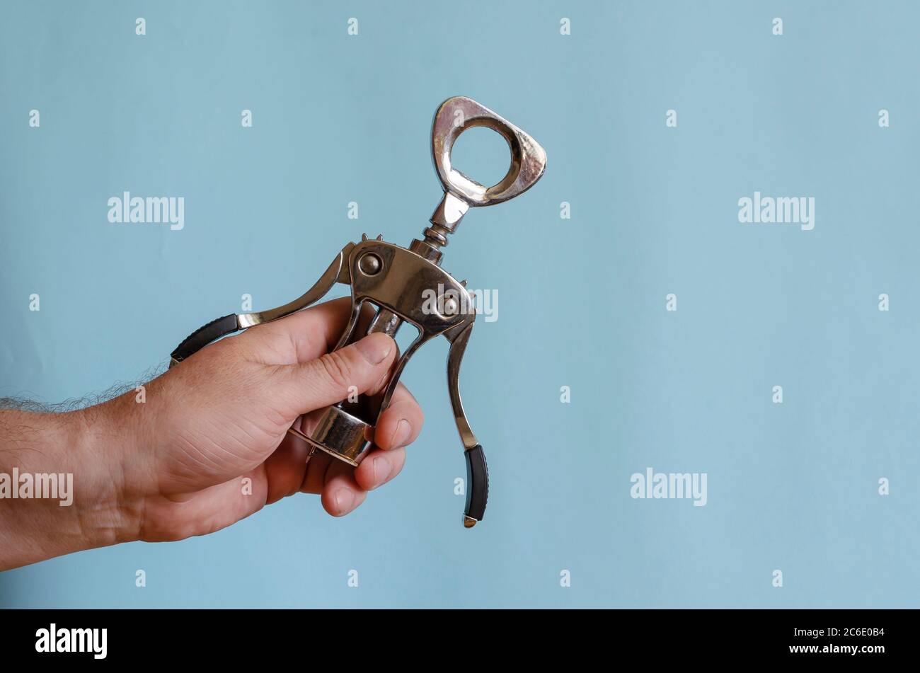 L'uomo adulto tiene in mano un cavatappi di metallo. Stappatura di bottiglie di vino. Maschio di razza europea, 43-45 anni. Utensili da cucina Foto Stock