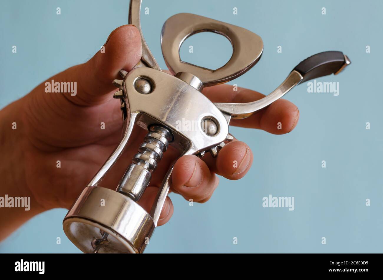 L'uomo adulto tiene in mano un cavatappi di metallo. Stappatura di bottiglie di vino. Maschio di razza europea, 43-45 anni. Utensili da cucina Foto Stock