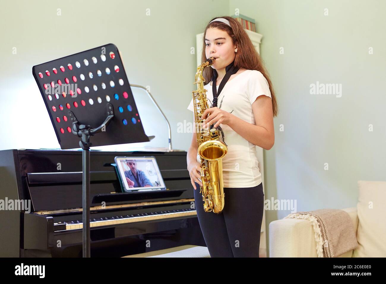 Ragazza che prende online sassofono lezione a casa Foto Stock