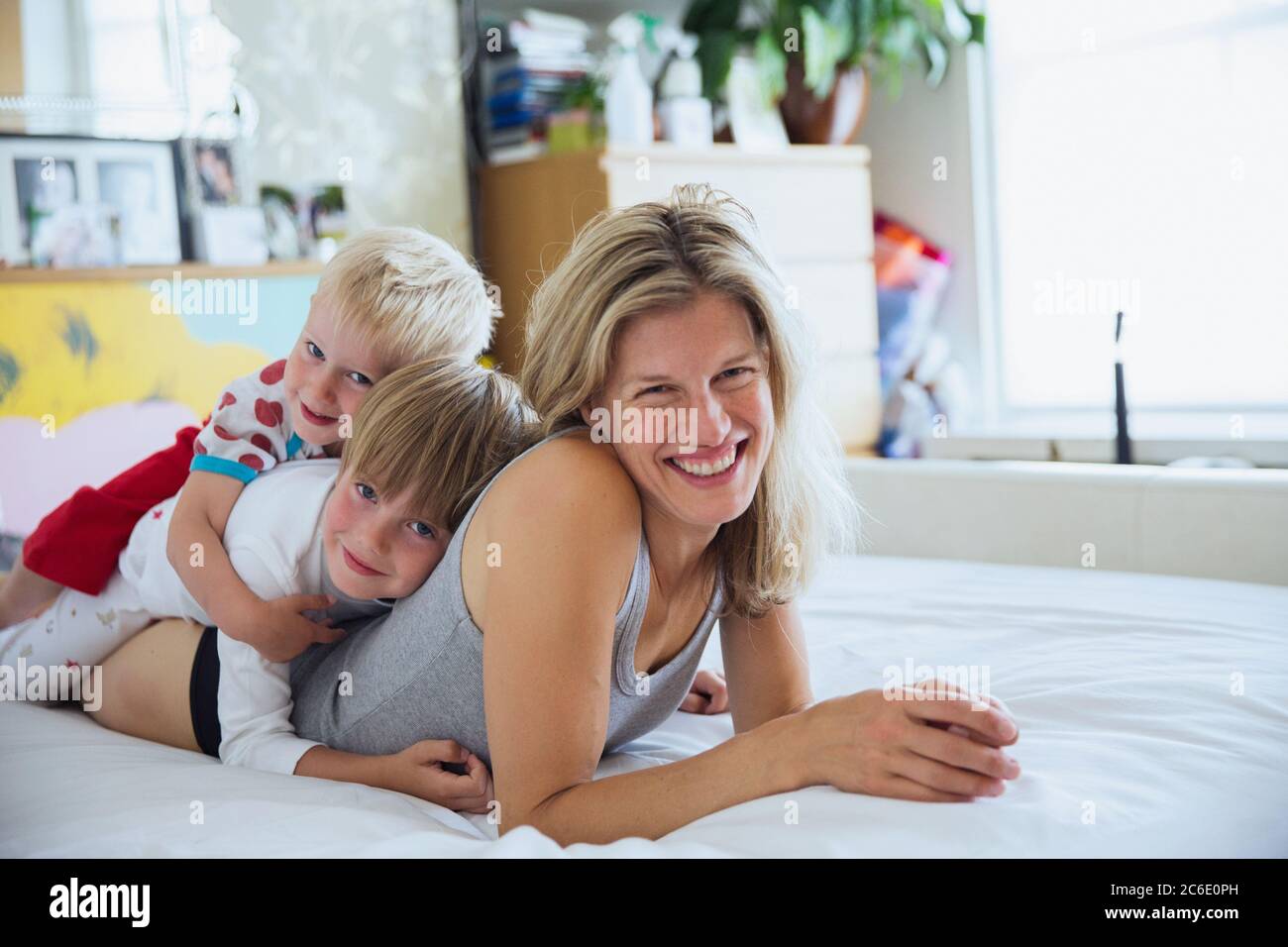 Ritratto di madre con figli a letto che si stendono uno sopra l'altro Foto Stock
