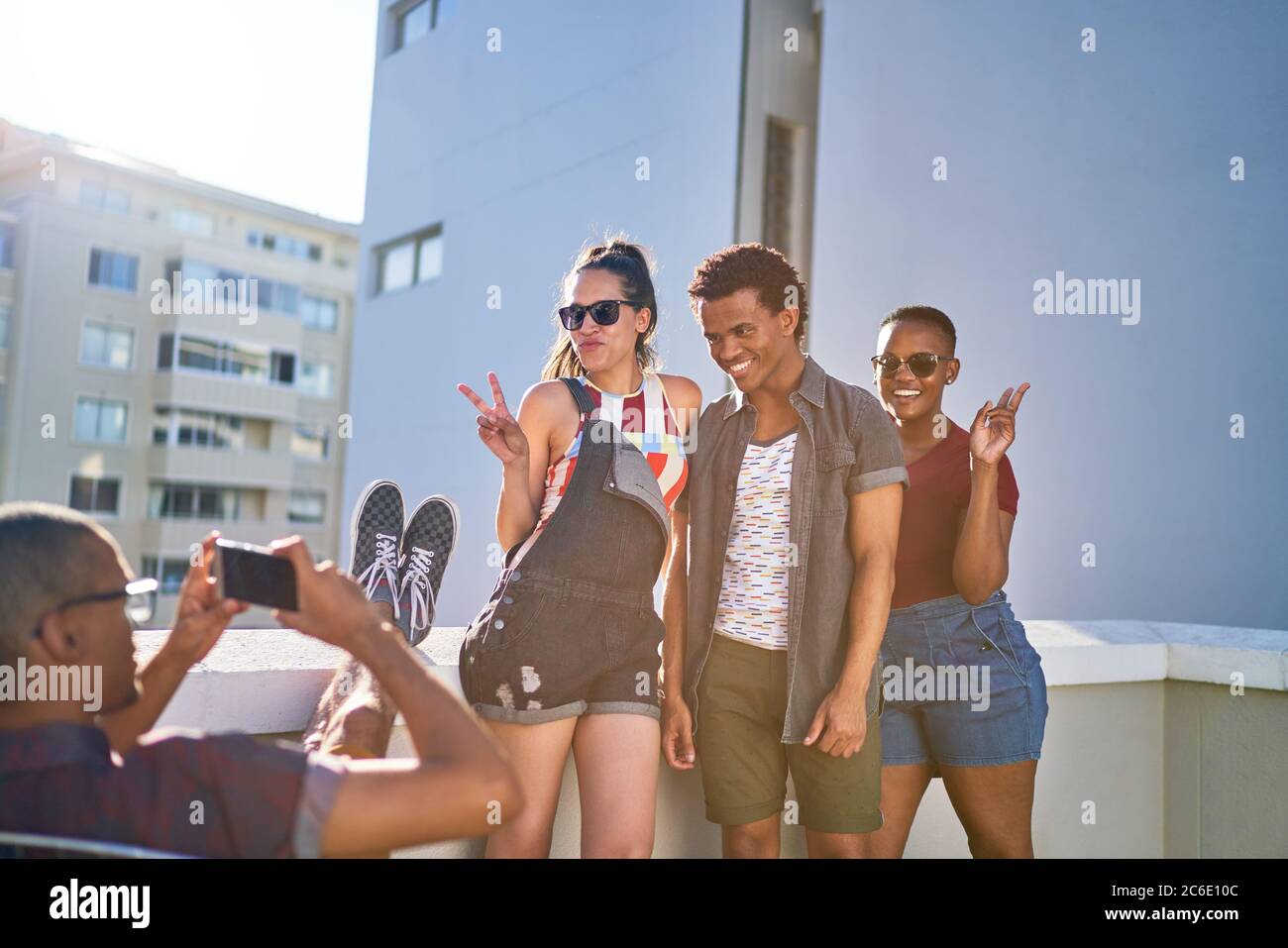 Amici giovani divertenti e divertenti che posano per una foto sul tetto soleggiato Foto Stock