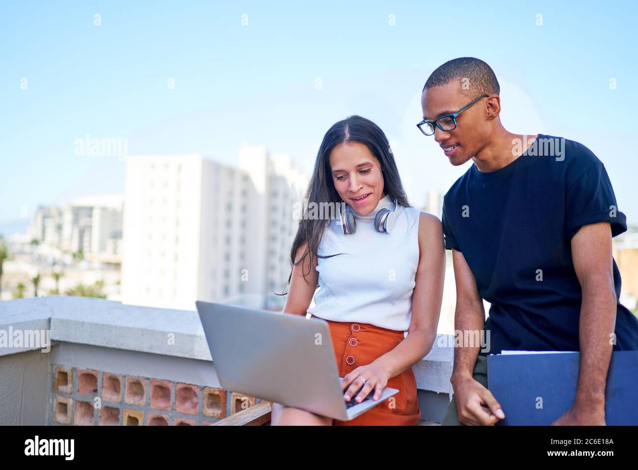 Giovani uomini d'affari con computer portatile che lavorano sul tetto urbano Foto Stock