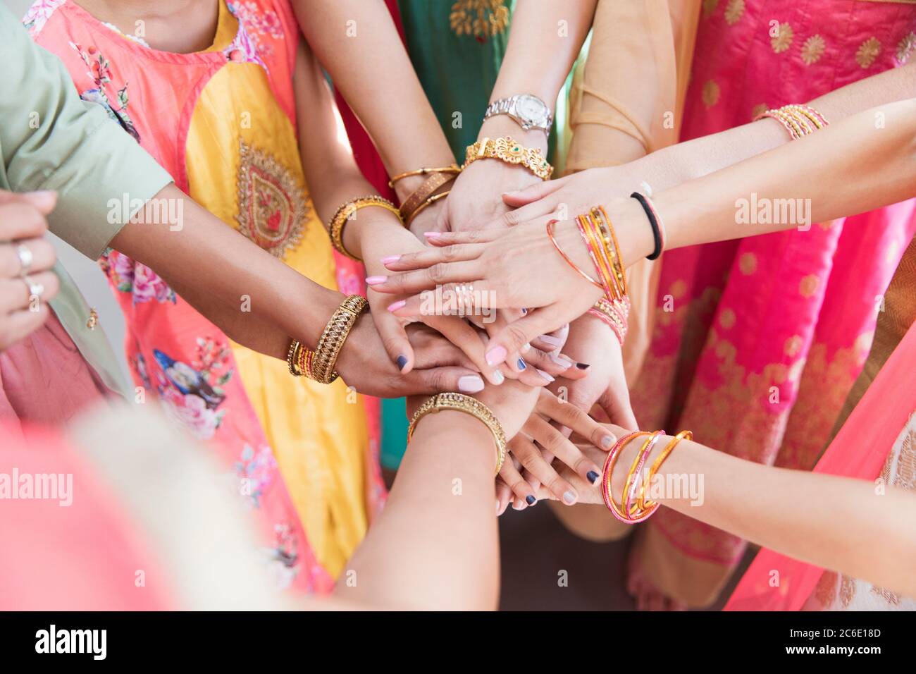 Donne indiane in braccialetti che si uniscono le mani in huddle Foto Stock