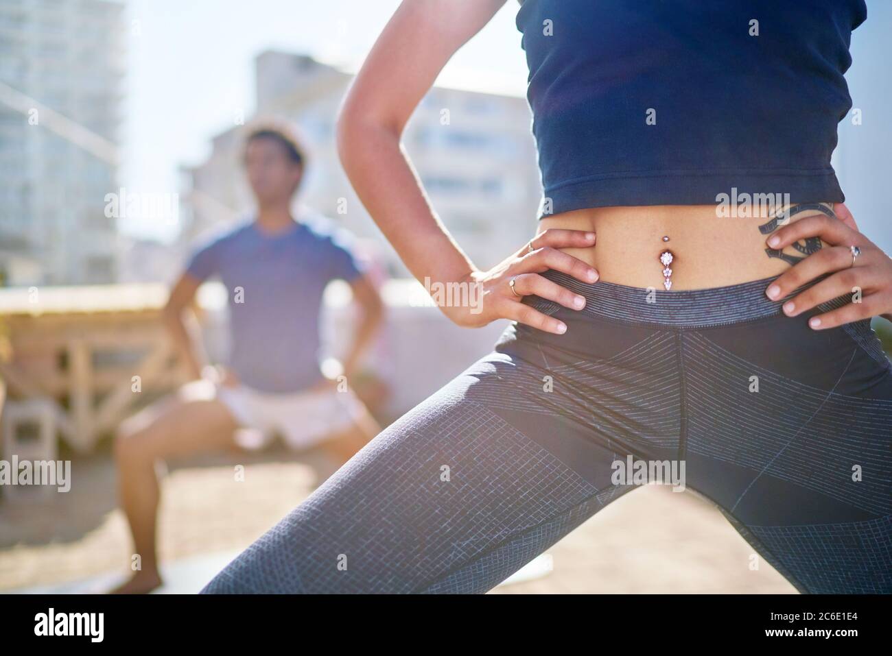 Primo piano giovane donna con pancia piercing pratica yoga sul balcone Foto Stock