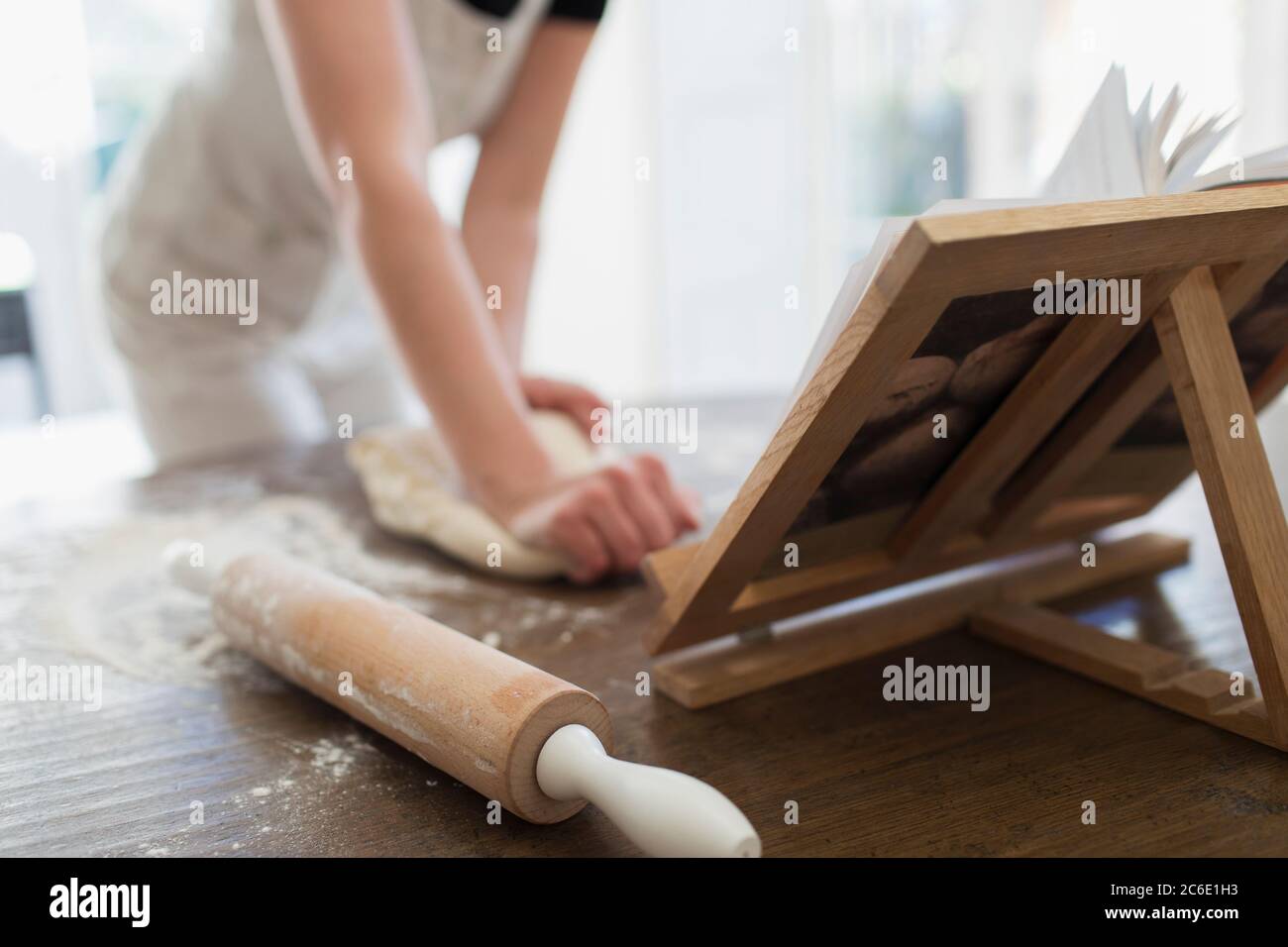 Donna impastare l'impasto al libro di cucina Foto Stock