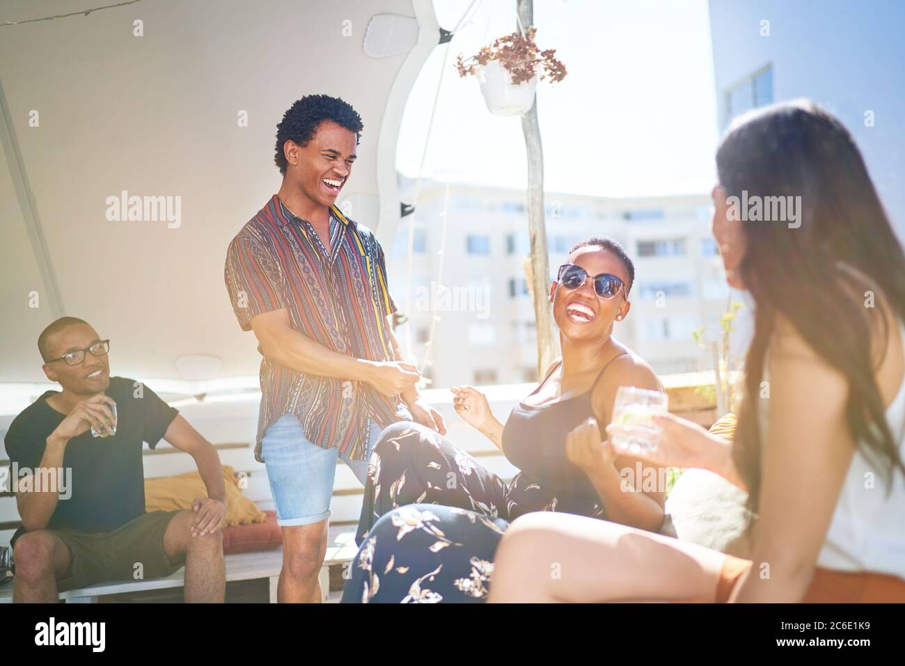 Felici i giovani amici che si affacciano sul soleggiato tetto urbano Foto Stock