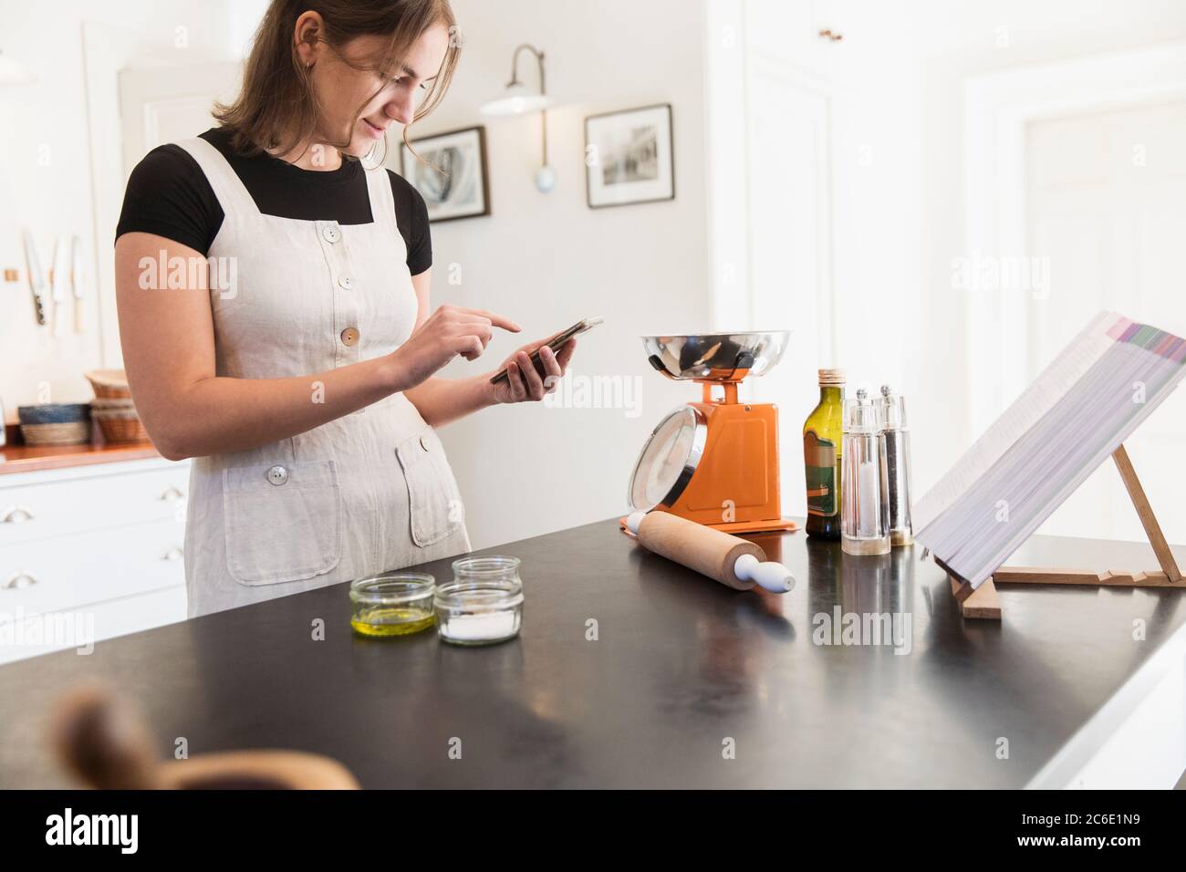 Ragazza adolescente con cottura smartphone in cucina Foto Stock