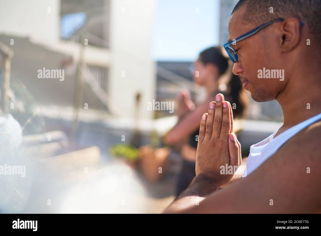 Sereno giovane uomo che pratica yoga sul patio soleggiato Foto Stock
