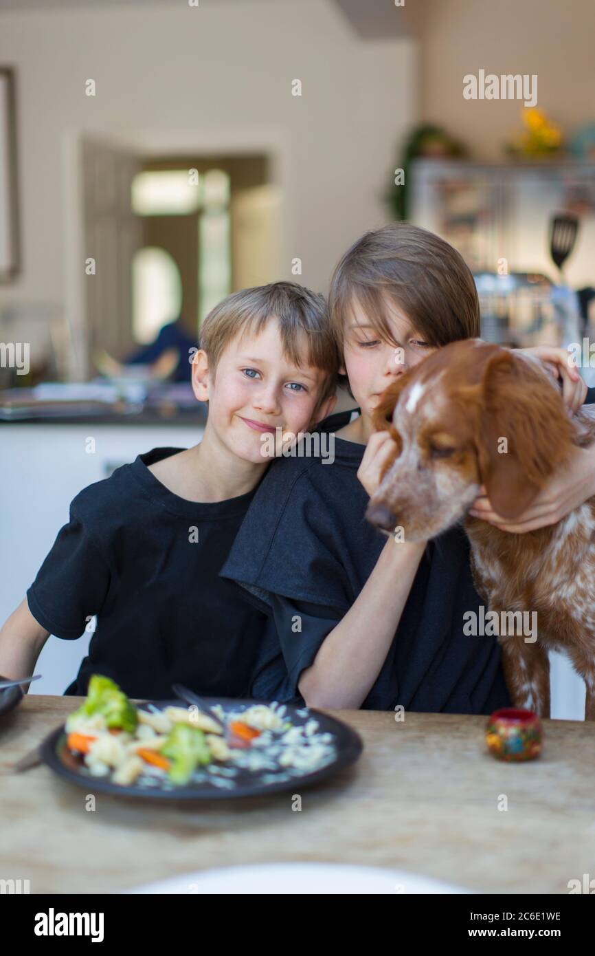 Ritratto fratelli con cane mangiare al tavolo da pranzo Foto Stock