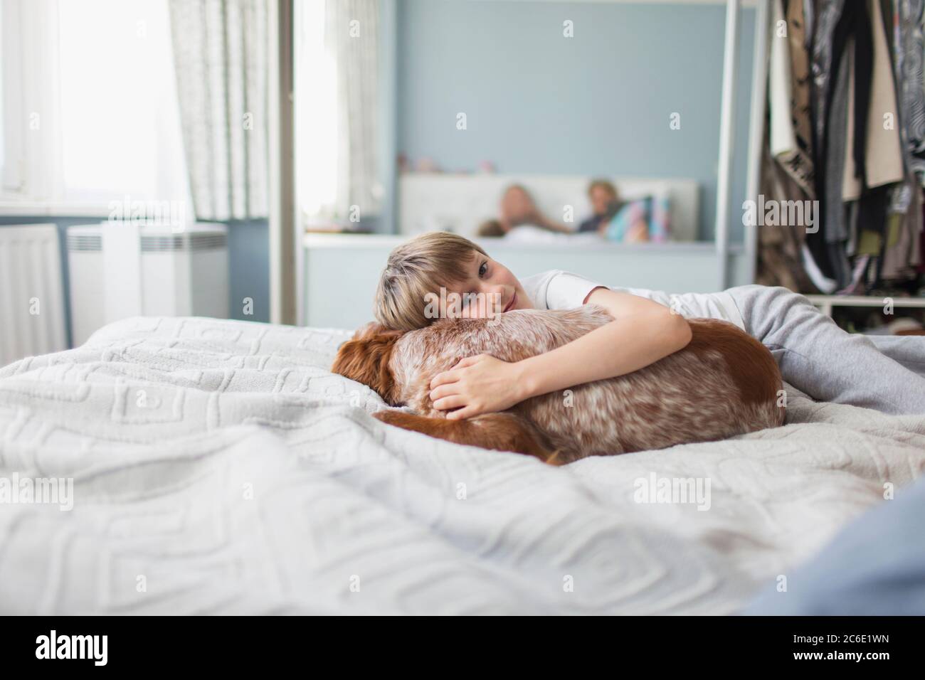 Ritratto carino ragazzo coccolando cane sul letto Foto Stock