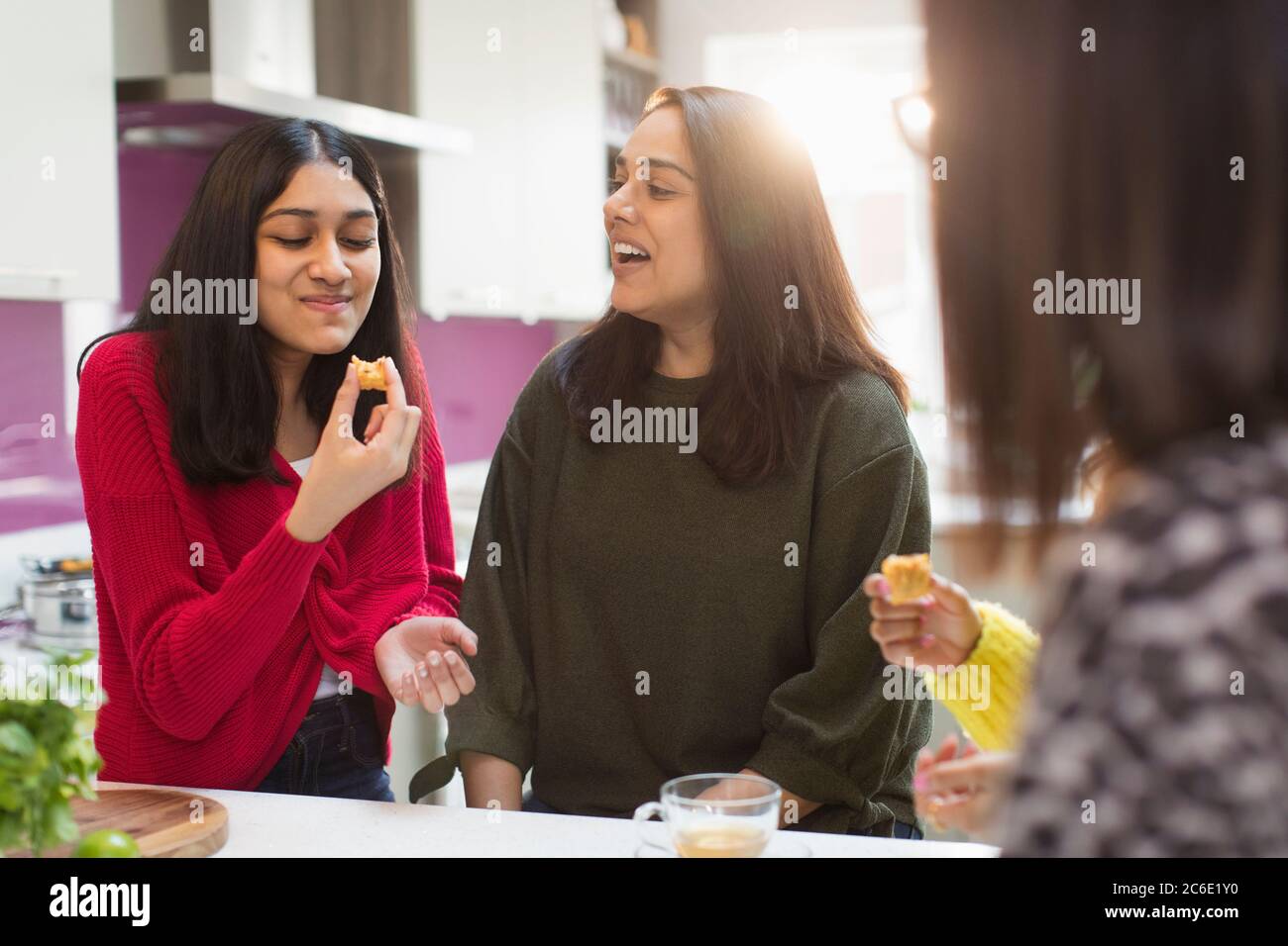 Donne felici che mangiano e parlano in cucina Foto Stock