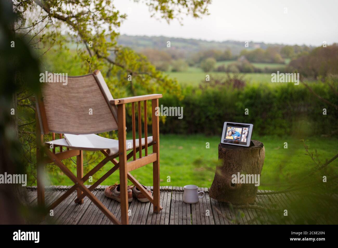 Chat video degli amici sullo schermo del tablet digitale su un patio idilliaco Foto Stock