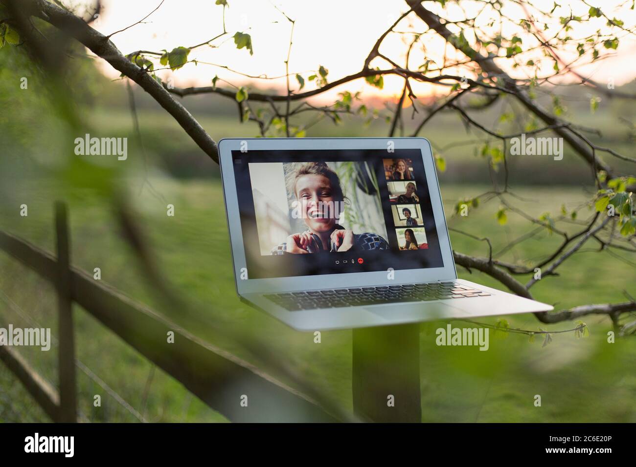 Video chat degli amici sullo schermo del laptop su un palo di recinzione rurale Foto Stock