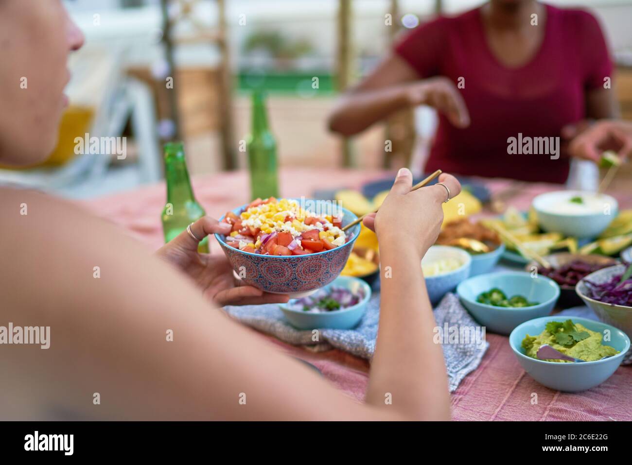 Giovane donna che mangia il pranzo al tavolo del patio Foto Stock