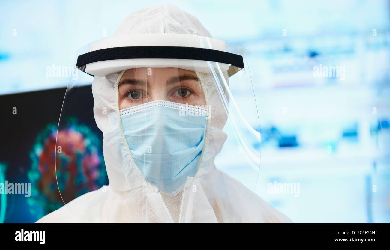 Ritratto sicuro scienziato femminile in tuta pulita studiando coronavirus Foto Stock