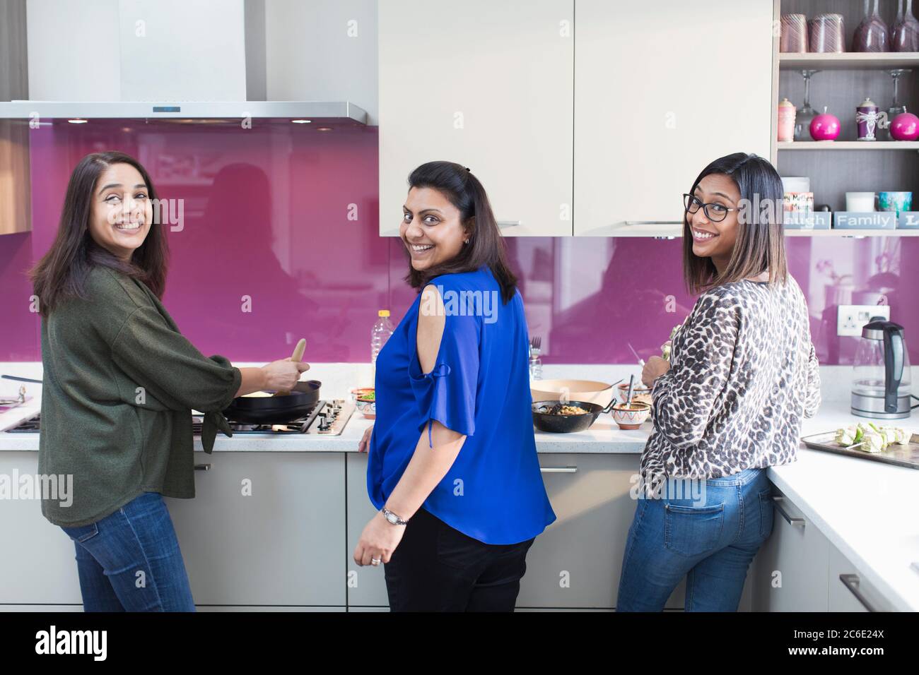 Ritratto felici sorelle indiane che cucinano cibo in cucina Foto Stock