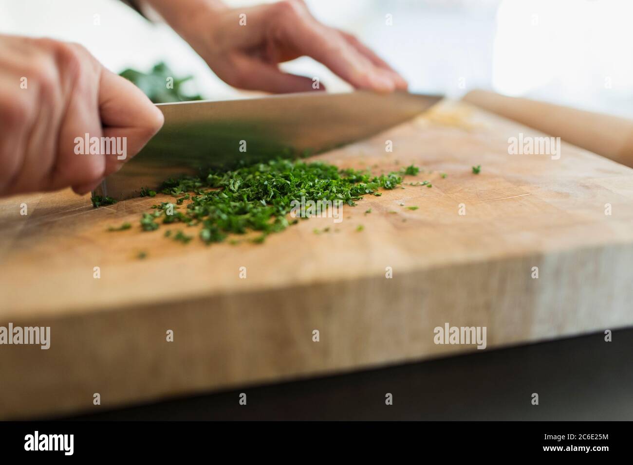 Primo piano donna che taglia erbe fresche con coltello sul tagliere Foto Stock