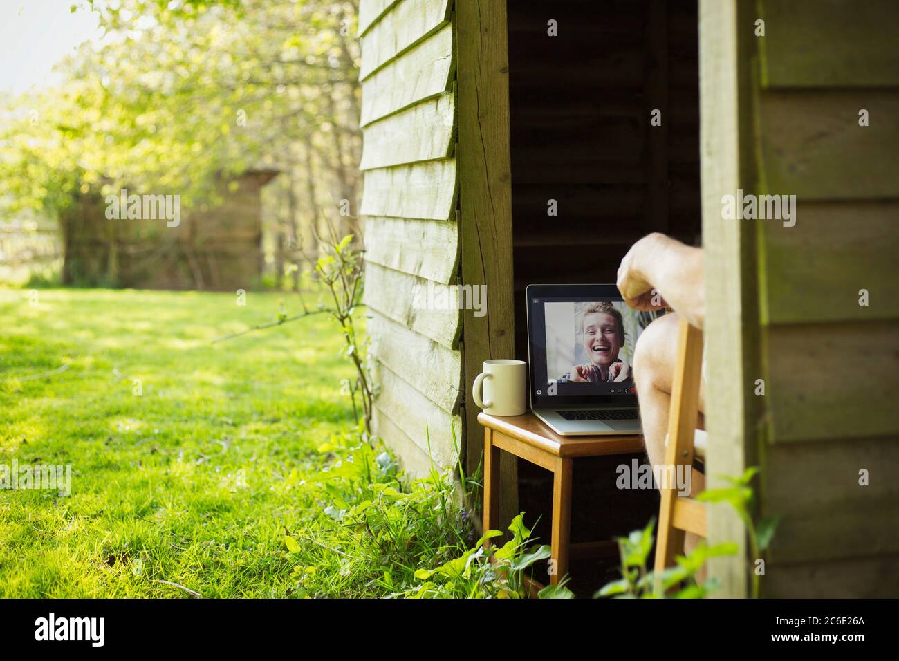 Uomo video chattando con gli amici su un computer portatile da giardino capanna Foto Stock