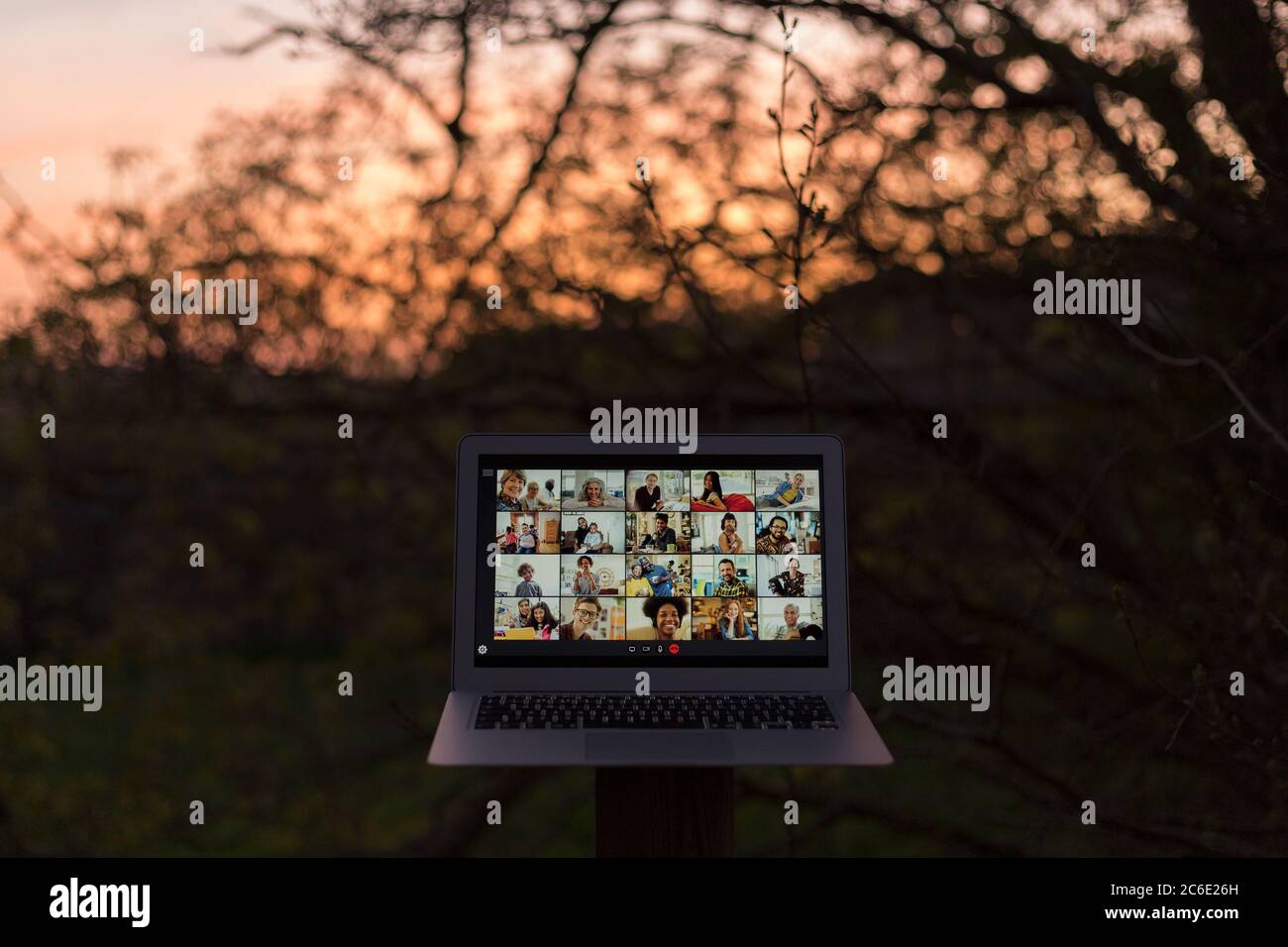 Amici che videochattano sullo schermo del computer portatile in giardino al tramonto Foto Stock