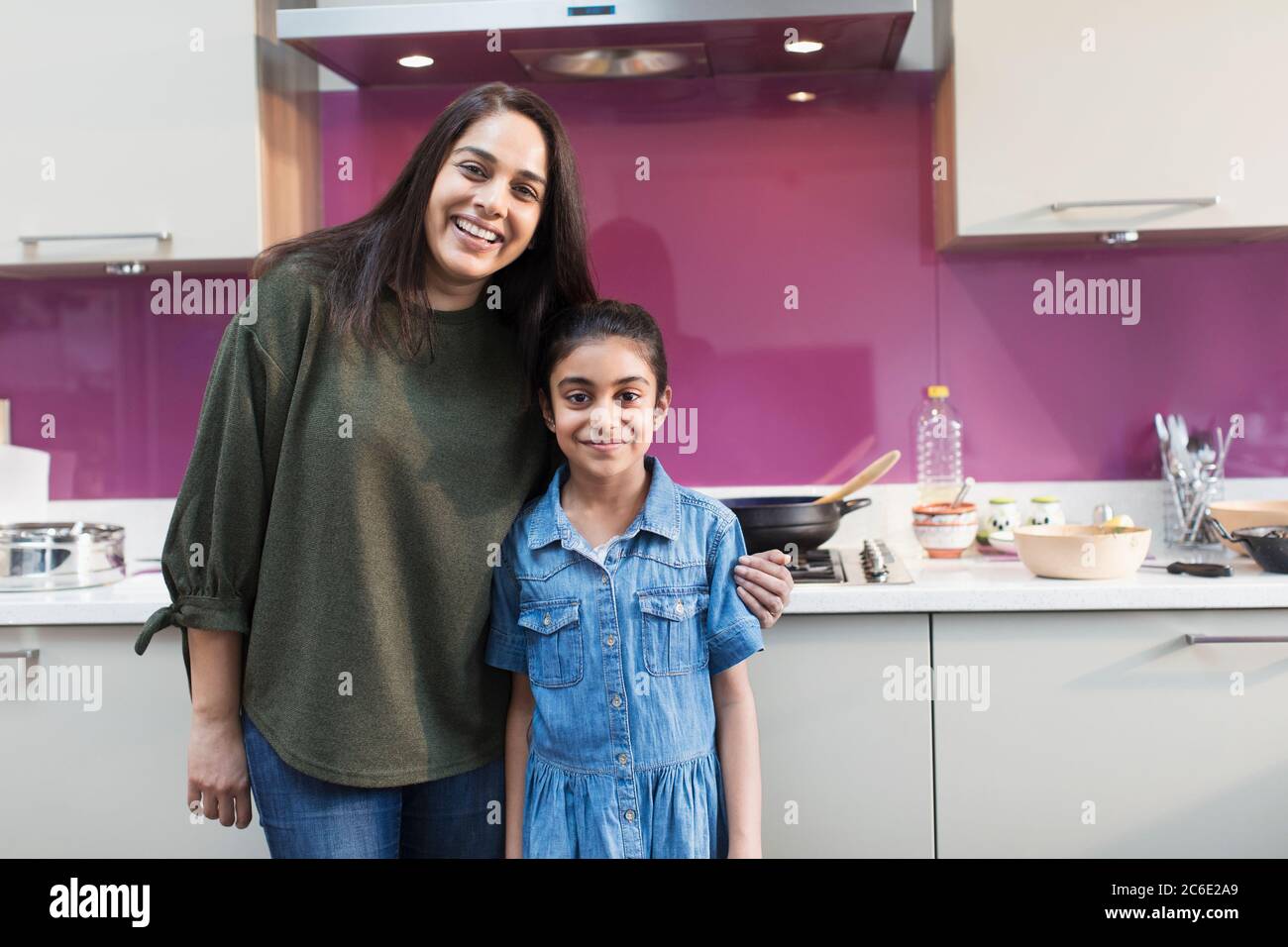 Ritratto felice madre indiana e figlia che cucinano cibo in cucina Foto Stock