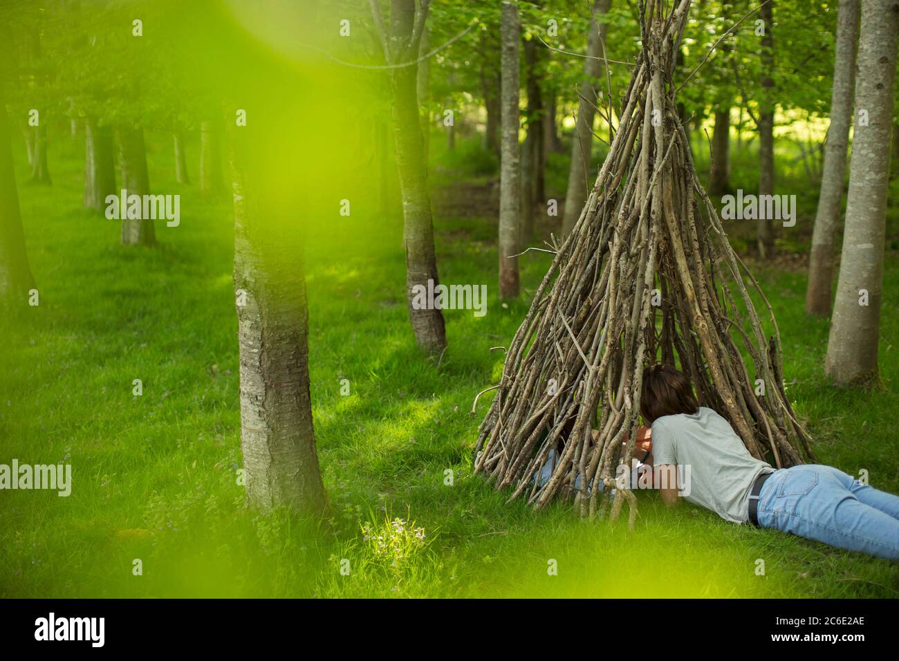 Donna che si rilassa in branca teepee in bosco Foto Stock