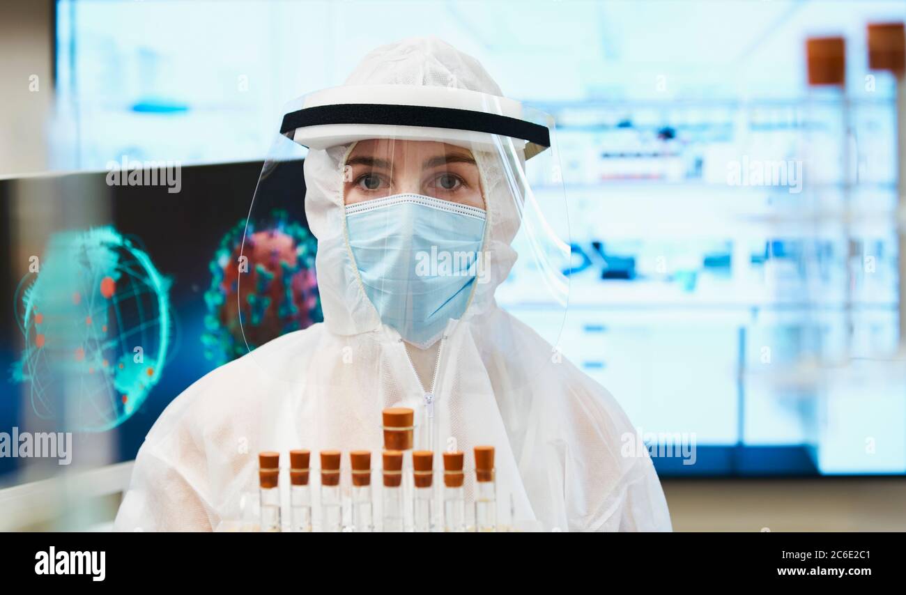 Ritratto scienziato femminile in tuta pulita studiando il vaccino del coronavirus Foto Stock