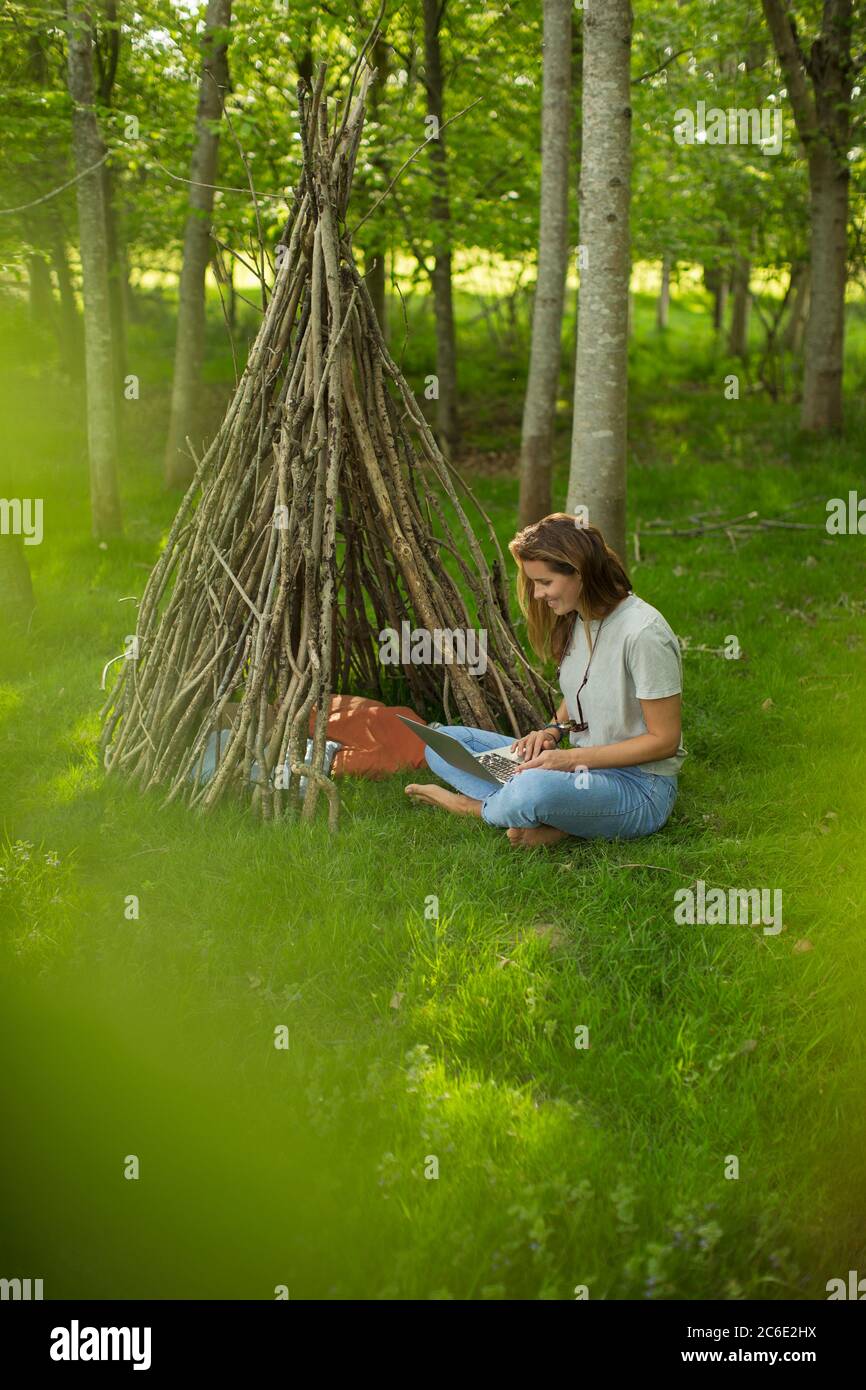 Donna con computer portatile rilassante in branca teepee in legno Foto Stock