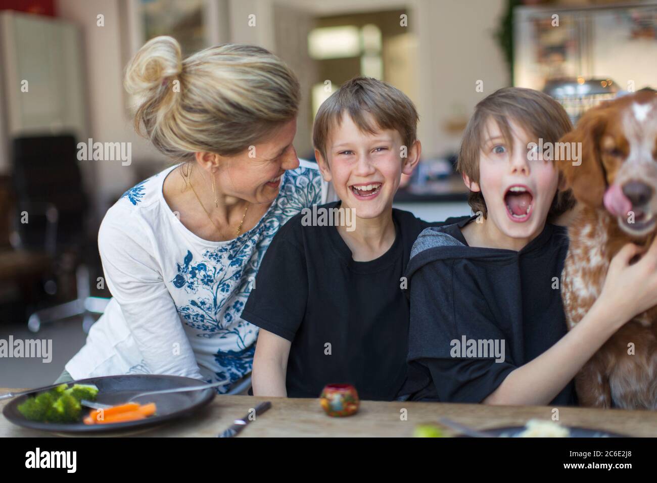 Ritratto felice famiglia con cane al tavolo da pranzo Foto Stock