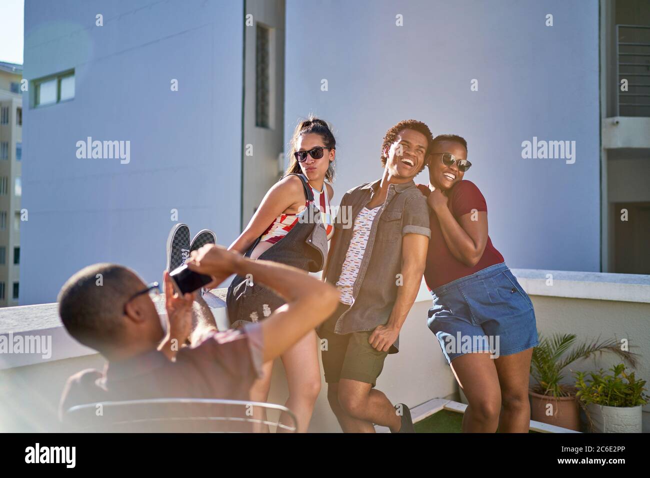 Divertenti giovani amici che posano per una foto sul soleggiato balcone urbano Foto Stock