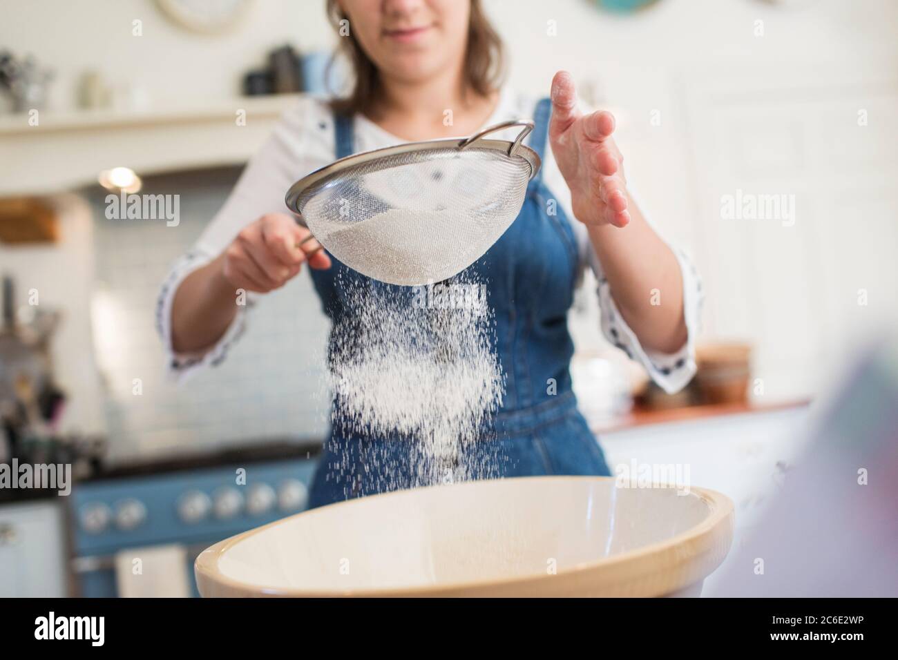 Teenage ragazza setacciando farina in cucina Foto Stock