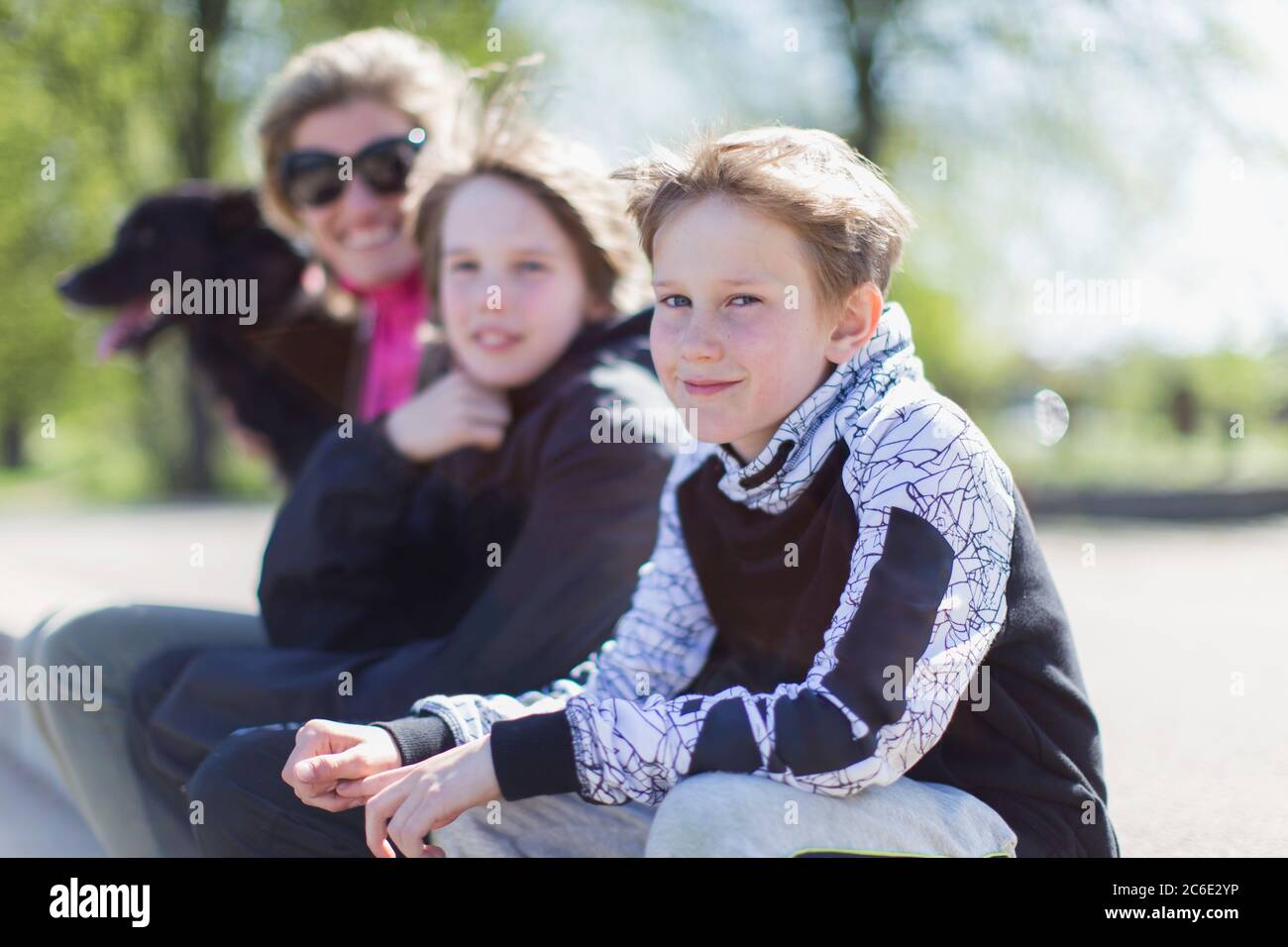 Ritratto madre e figli con cane in parco soleggiato Foto Stock