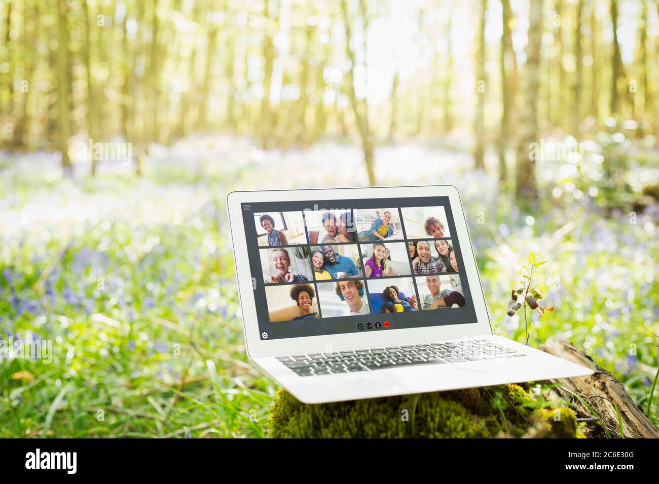 Amici che videochattano sullo schermo del laptop in legno soleggiato Foto Stock