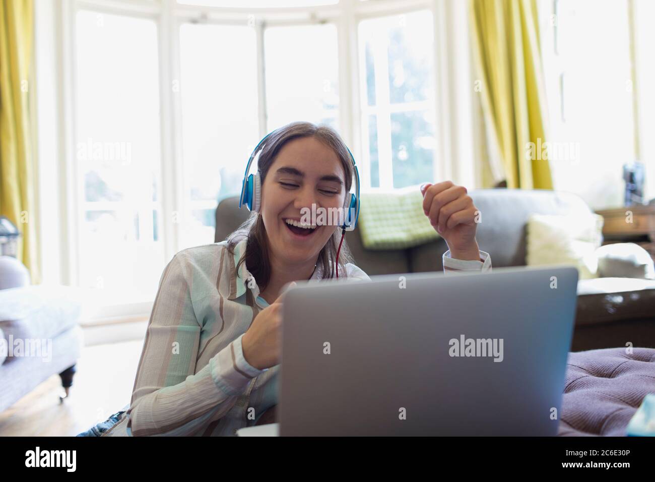 Felice adolescente con le cuffie video chattando al laptop Foto Stock