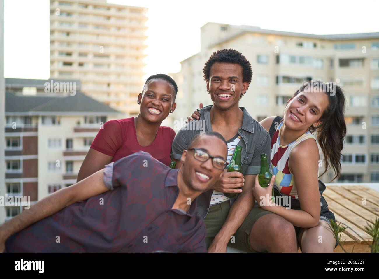 Ritratto felici giovani amici appesi sul soleggiato tetto urbano Foto Stock