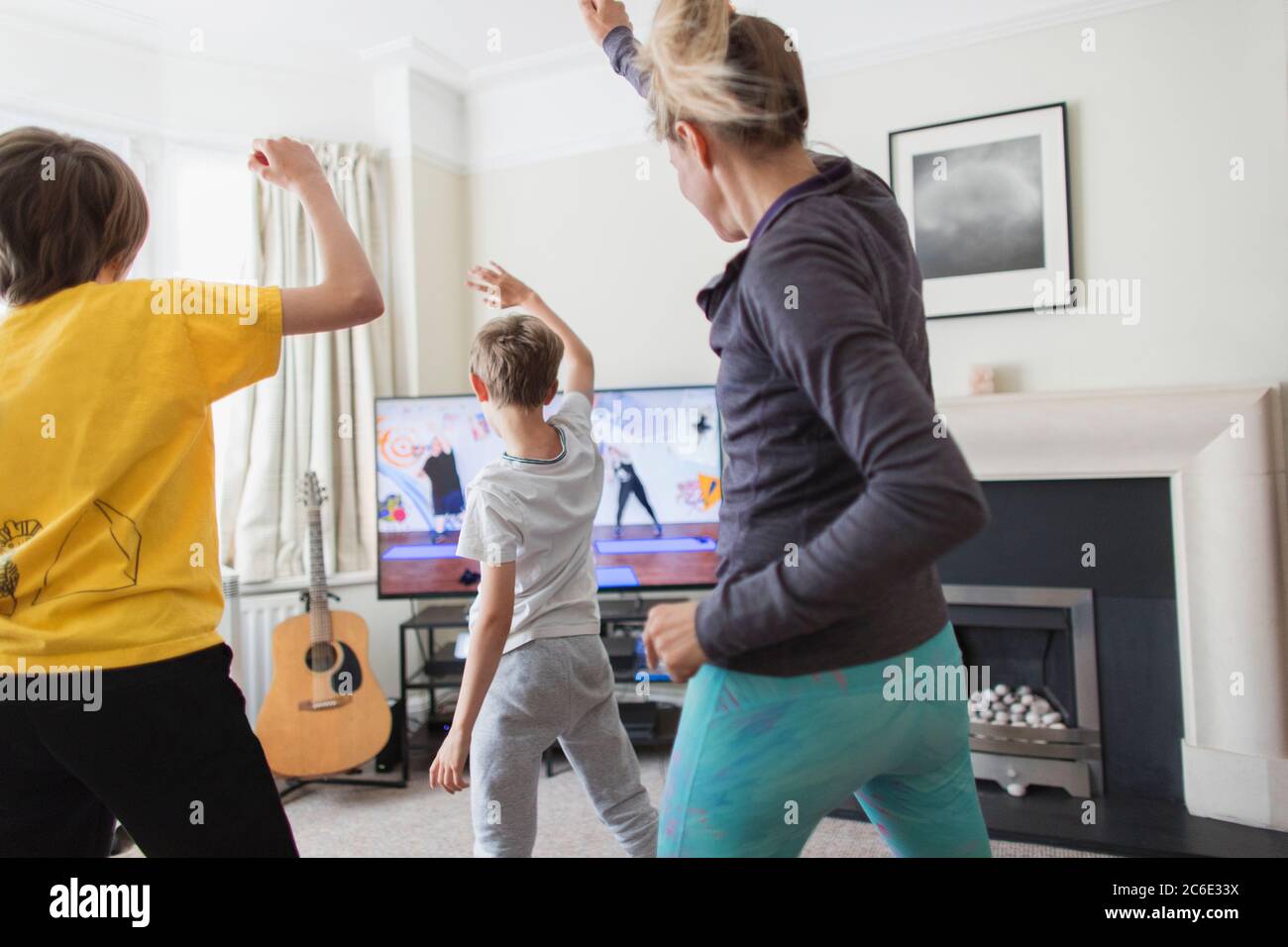 Madre e figli che si esercitano in TV in soggiorno Foto Stock