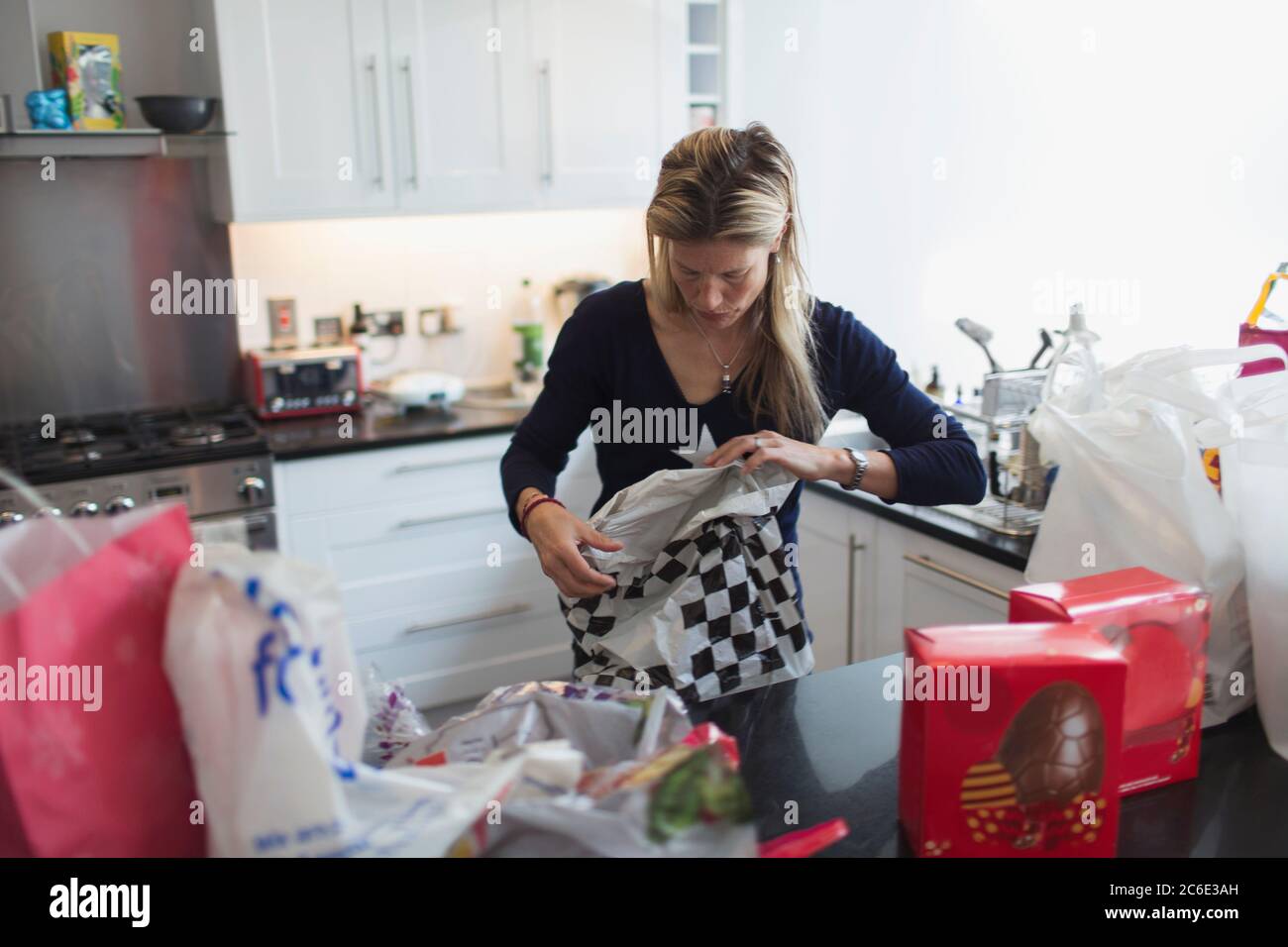 Donna che disincarna i generi alimentari in cucina Foto Stock